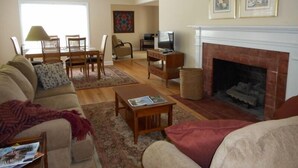 A living room with a fireplace, a television, a dining area, and a sofa.