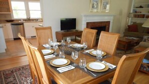 A dining room with a wooden table set for six, surrounded by chairs.