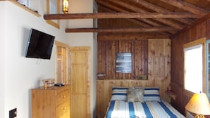 Une chambre dans une cabane en bois, avec un lit, une commode et un téléviseur.