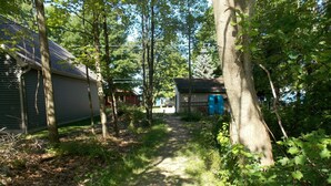 Un sentier étroit et terreux qui mène à une maison entourée d’arbres.