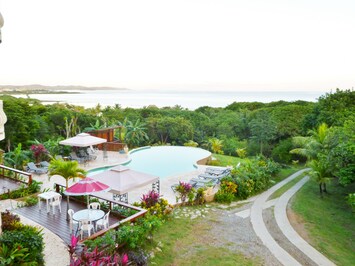 View of patio, pool, road and sea from condo balcony