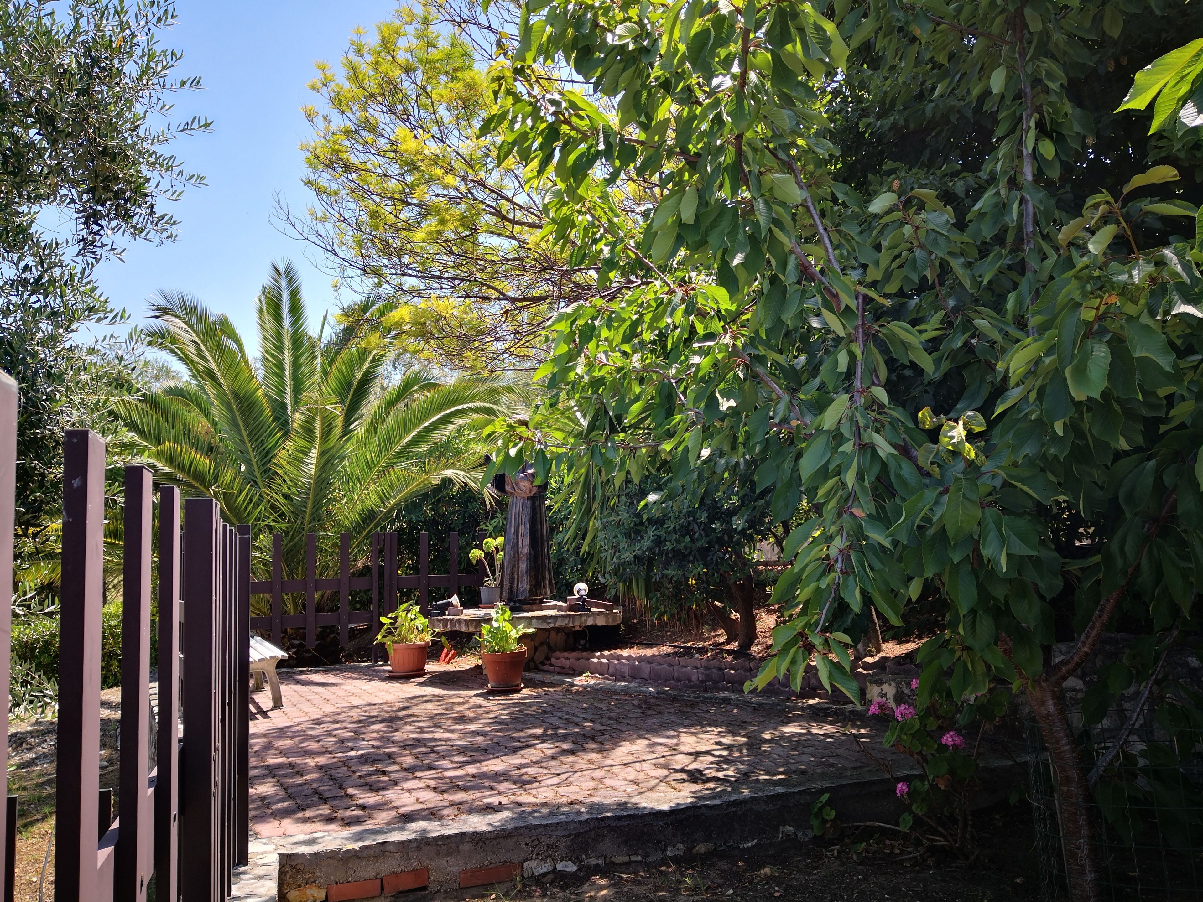 Un jardín pavimentado con macetas y un cerco de madera.