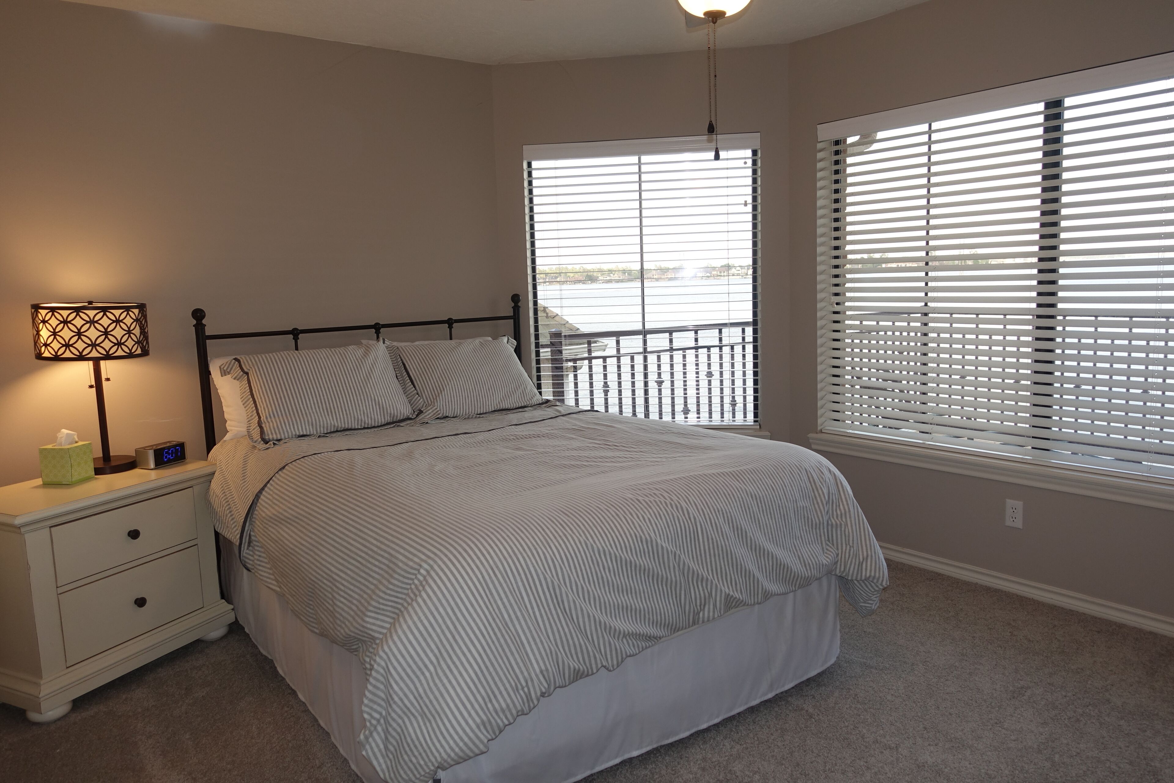 A bedroom with a bed, nightstand, lamp, and a window with blinds.