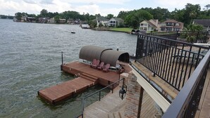 Un muelle de madera que se adentra en un lago, con una zona de estar cubierta y una barandilla.