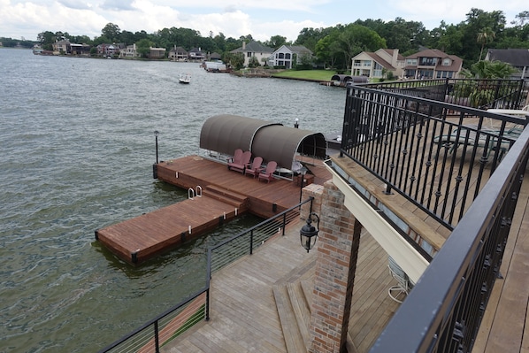 A wooden dock extending into a lake with a covered seating area and a railing.