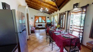 A dining area with a red tablecloth, a refrigerator, and a television in the background. - Quinta Teca with two pools near Playa Hermosa beach (Playa Hermosa)