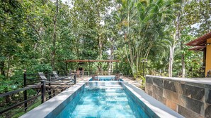 A rectangular pool with clear blue water, surrounded by a stone wall and lush greenery. - Quinta Teca with two pools near Playa Hermosa beach (Playa Hermosa)