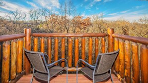 A wooden deck with two metal chairs facing a wooden fence. - 💦Skinny Dippin🌲Private Indoor Pool, Hot Tub, Theater & Game Room (Sevierville)