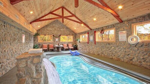 An indoor swimming pool with stone walls and wooden beams. - 💦Skinny Dippin🌲Private Indoor Pool, Hot Tub, Theater & Game Room (Sevierville)