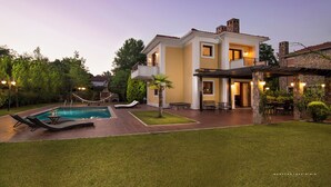 Une maison à deux étages avec une piscine, un espace extérieur aménagé et une pelouse bien entretenue.