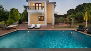 Une maison à deux étages avec une piscine, un balcon et un espace salon extérieur.