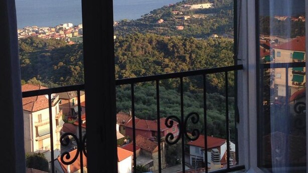 A balcony with a view of a coastal town and the sea.