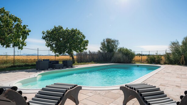 A rectangular swimming pool with a tiled deck, surrounded by lounge chairs and a fence. - Farmhouse with swimming pool 2 km away from the sea (Piombino (LI))
