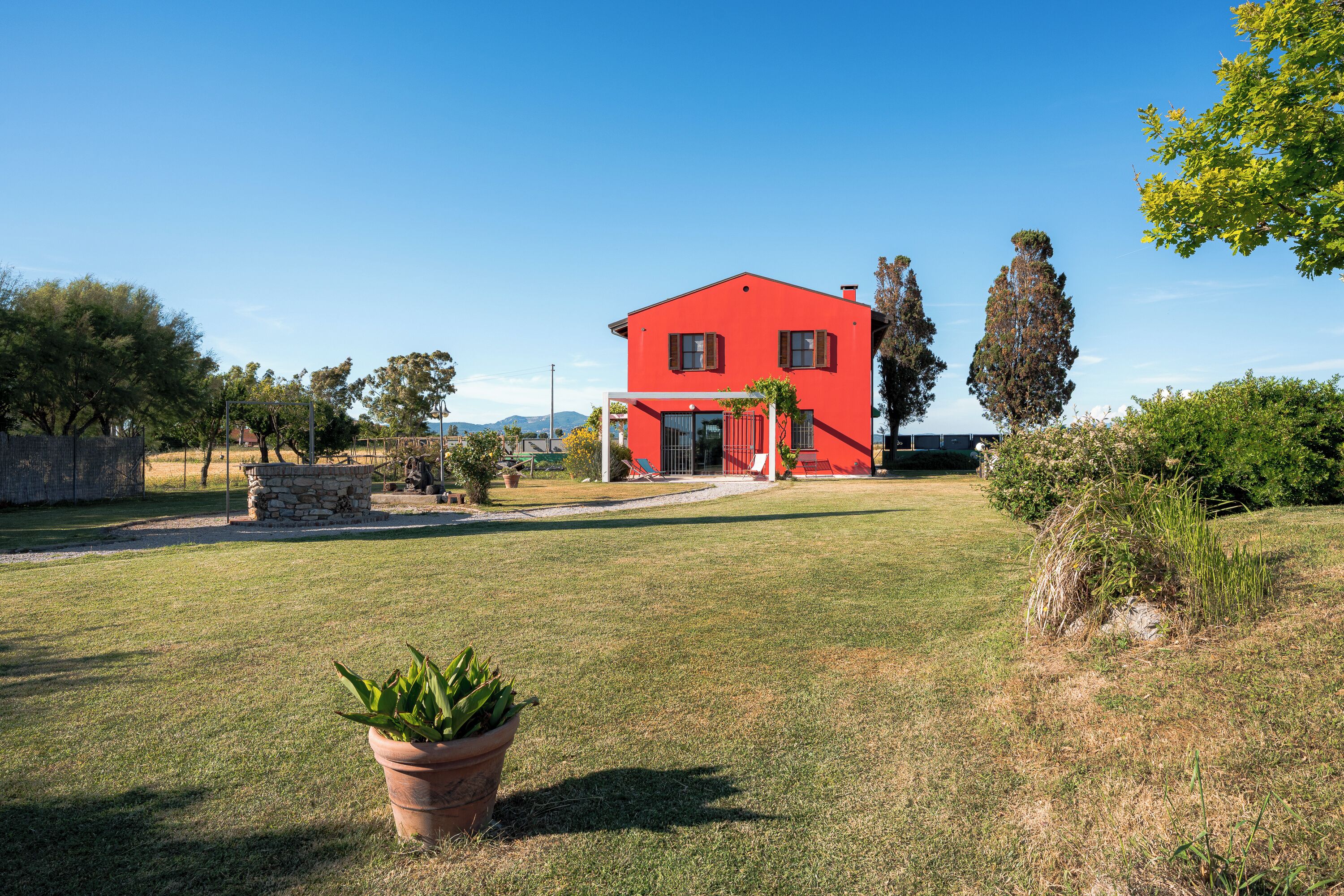 Una casa roja con entrada empedrada y césped al frente.