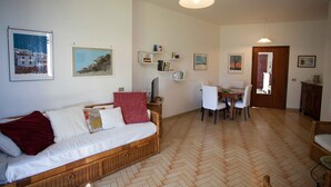 Ein Wohnzimmer mit einer Couch, einem Esstisch mit Stühlen und einem fußbodenbelag mit Zickzackmuster.