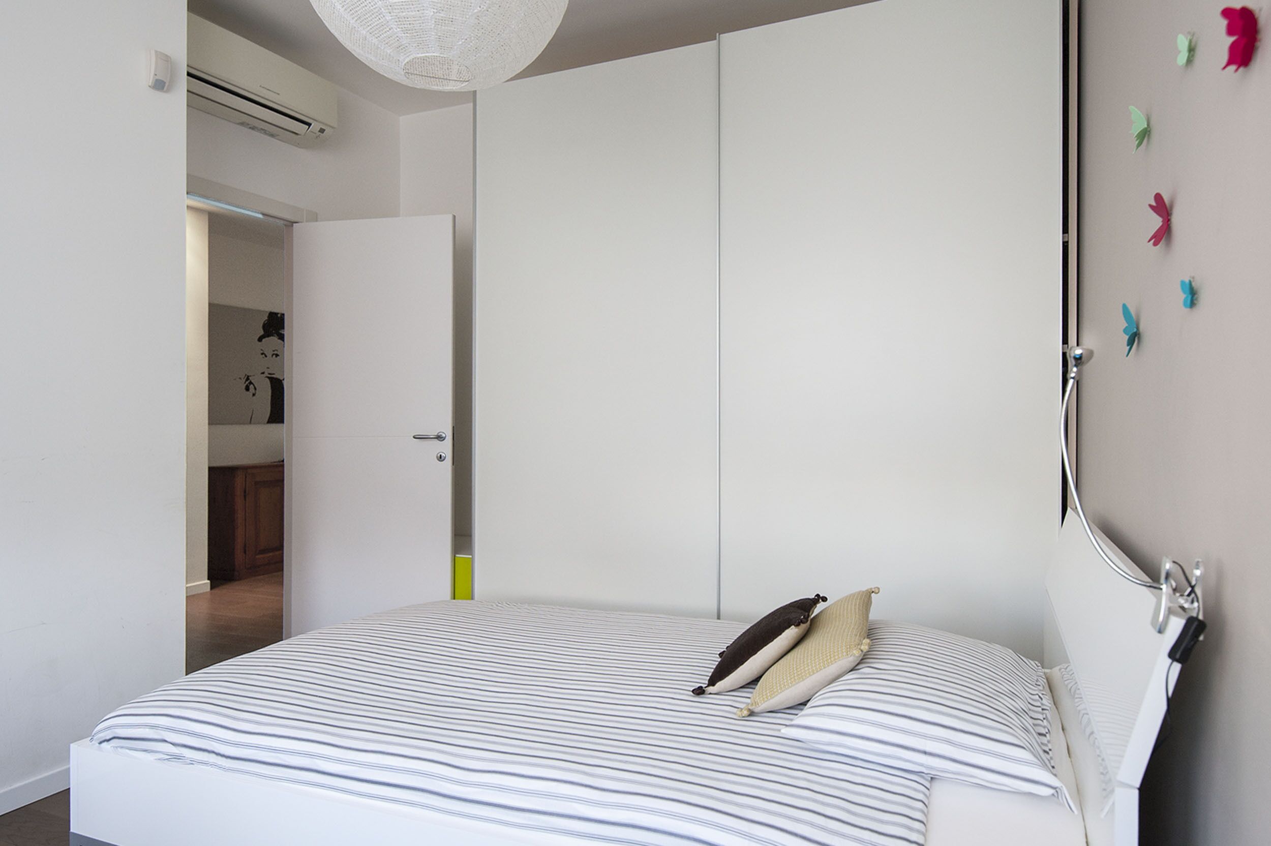 A bedroom with a bed, a wardrobe, and a door leading to a bathroom.