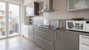 Cocina moderna con un amplio ventanal, electrodomésticos de acero inoxidable y vistas al balcón.