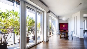 Una habitación amplia con ventanas grandes, un comedor con una mesa y sillas de madera, y un armario rojo.