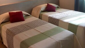 Due letti singoli con copriletti a fantasia, una testiera e un applique a parete.