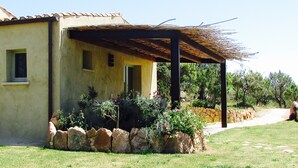 Un edificio con un portico coperto, un muro in pietra e un prato verde.