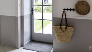 Una habitación con una puerta blanca, una cesta tejida colgada en la pared y un tapete de fibras naturales.