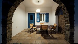 A dining area with a stone archway, a table with chairs, and a hanging light fixture.