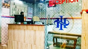A reception area with a reception desk, a computer, a fan, and a bench. - Hotel Shalimar Int'l (Dhaka)