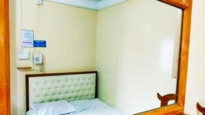 A single bed with a wooden headboard in a room with a plain wall and a wooden chair. - Hotel Shalimar Int'l (Dhaka)