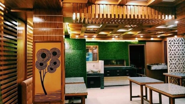A modern interior with wooden paneling, a green wall, and a decorative panel with a tree design. - Hotel Shalimar Int'l (Dhaka)