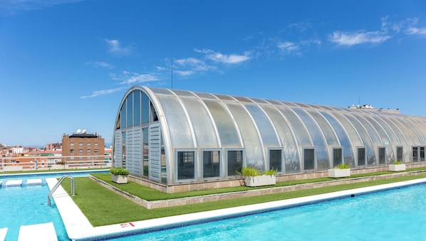 Una piscina con una estructura de invernadero de vidrio adyacente.