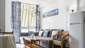 A modern living room with a sofa, a dining table, and a wicker chair. - 2 Bed Apartment with communal pool (Nerja)