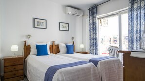 A hotel room with two beds, a wooden dresser, a desk, and a window with curtains. - 2 Bed Apartment with communal pool (Nerja)