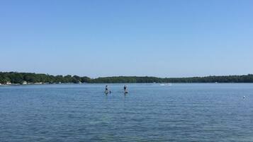 A calm lake with two people paddleboarding.