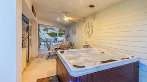 Ein Wellnessbereich mit Whirlpool, Deckenventilator und Sitzgelegenheit im Freien.