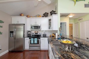 Una cocina moderna con gabinetes blancos, electrodomésticos de acero inoxidable y encimera de granito.