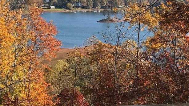 A view of a lake surrounded by autumn-colored trees and hills. - HOTLIPS AT COLLINWOOD upstairs Price is on the website  Down stairs $125 extra (Hiawassee)