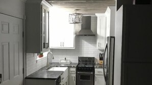 A compact kitchen with white cabinets, a stainless steel stove, and a refrigerator. - HOTLIPS AT COLLINWOOD upstairs Price is on the website  Down stairs $125 extra (Hiawassee)