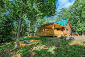 Escape to a serene forest retreat with a cozy cabin surrounded by a lush garden and a spacious deck for relaxation.