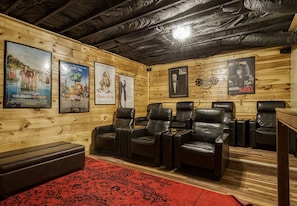 Une pièce aux murs en bois, avec des fauteuils en cuir noir et une moquette rouge.