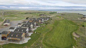 Un barrio residencial con casas alineadas, un campo de golf y una masa de agua al fondo.