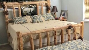 A bed with a wooden frame and a bench at the foot. - Welcome To Our "Home To The Outdoors" (La Pine)