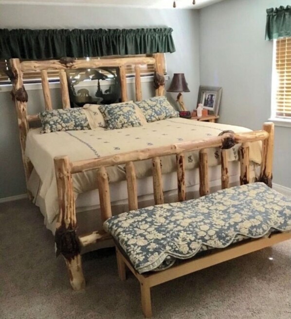 Uma cama com estrutura de madeira e um banco ao pé.