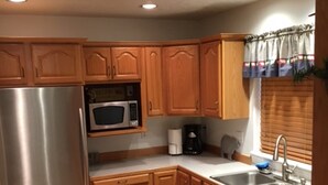 A kitchen with wooden cabinets, stainless steel appliances, a microwave, a coffee maker, and a sink. - Welcome To Our "Home To The Outdoors" (La Pine)