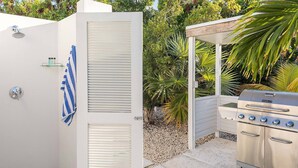 A patio area with a grill, a covered seating area, and a white door with a towel hanging on it.