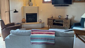 Een gezellige woonkamer met een open haard, een televisie en comfortabele zitplaatsen.