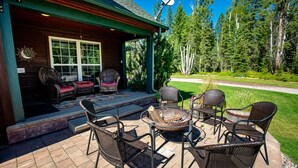 A covered patio with wicker furniture, a fire pit, and a satellite dish. - Blue Star Creekside Lodge  (Columbia Falls)