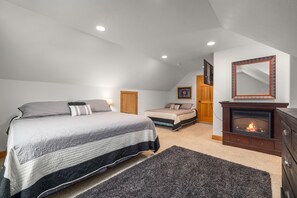 A bedroom with a large bed, a smaller bed, a fireplace, and a ceiling with recessed lighting. - Blue Star Creekside Lodge  (Columbia Falls)
