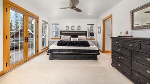 A bedroom with a bed, a dresser, a ceiling fan, and a large mirror. - Blue Star Creekside Lodge  (Columbia Falls)