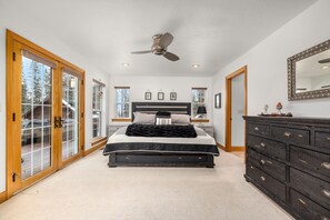 A bedroom with a bed, a dresser, a ceiling fan, and a large mirror. - Blue Star Creekside Lodge  (Columbia Falls)