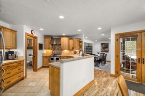 A modern kitchen with wooden cabinets, a central island, and a dining area with a view.